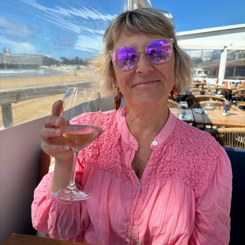 Isabelle, Fondatrice Chasarose Image d'Isabelle dans un restaurant de Plage, en train de profiter d'un moment apéritif comme on les aime.