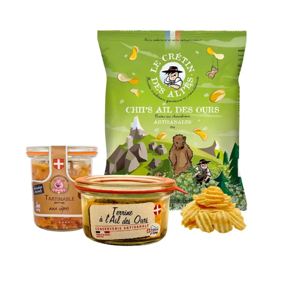 Un arrière plan de montagne, avec sur une table de pique nique, un paquet de chips ail des ours, une terrine à l'ail des ours et un tartinable aux cèpes. Parfait pour un apéro minute.